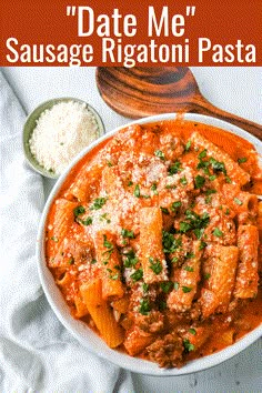 a white bowl filled with pasta and sauce next to a wooden spoon on top of a towel