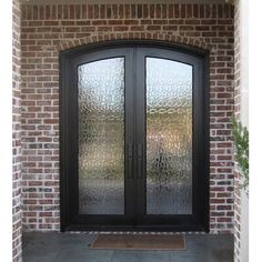 a black double door with frosted glass on the front of a brick building,