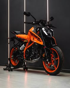 an orange motorcycle parked in front of a black wall