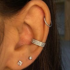 a close up of a person's ear with three different piercings on it