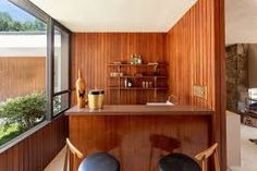 two chairs sitting in front of a bar next to a wall with wood paneling