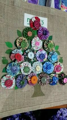 there is a tree made out of buttons on the back of a bag with purple flowers