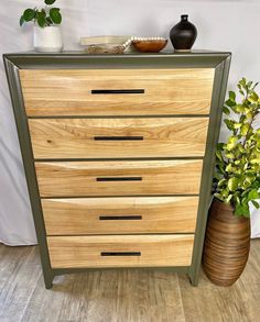 a wooden dresser sitting next to a potted plant