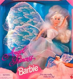 the barbie doll is in its box and has wings on her body, which are white