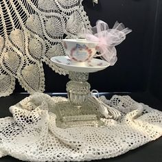 a white crocheted doily with a cup on top and saucer in the middle