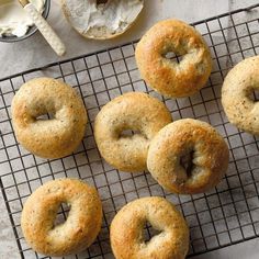 six bagels on a cooling rack next to a cup of coffee and spoons