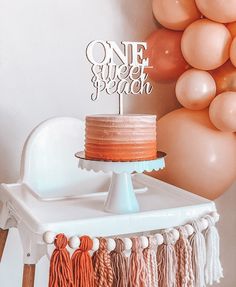 a cake on a table with balloons and a one - tiered cake topper