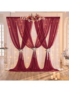 a room with red curtains and candles on the floor in front of it is decorated with flowers