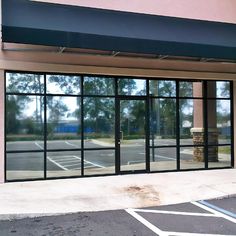 an empty parking lot in front of a building with glass doors that are open to the street