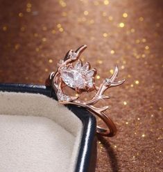 a close up of a ring in a box on a table with gold glitters