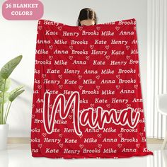 a woman holding up a blanket with the word mama printed on it in white and red