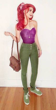 a woman with red hair and green pants holding a purse