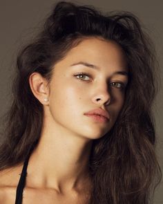 a woman with long brown hair wearing a black bra top and posing for the camera