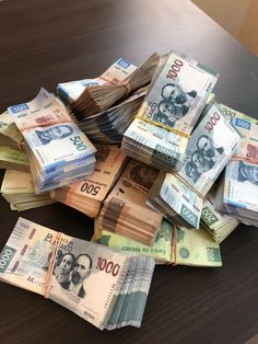 a pile of money sitting on top of a wooden table