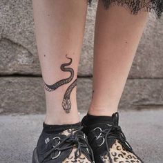 a woman's foot with a snake tattoo on her left ankle and leopard print shoes