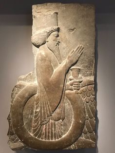 an ancient sculpture with a bird on it's back and a man holding a cup in his hand