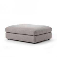 a grey ottoman sitting on top of a white floor