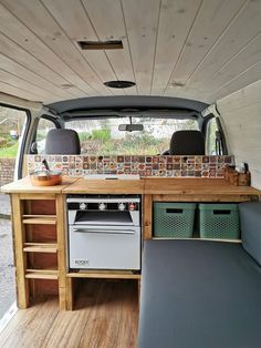 the interior of a van with wood flooring and an oven in the back area