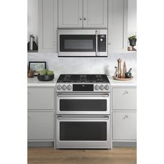 a silver stove top oven sitting inside of a kitchen next to white cupboards and counter tops