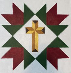 a cross is on the center of a quilted wall hanging ornament in red, green and gold