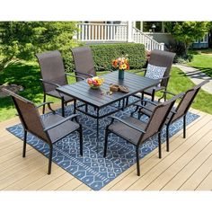 an outdoor table and chairs set on a blue area rug with flowers in vases