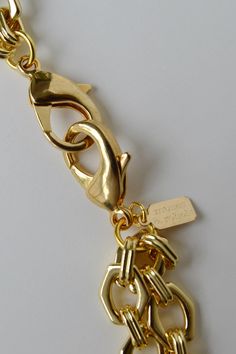 A bold hexagon link chain necklace in gold plated brass with a short strand and a second y-strand. The y-strand has a center connector gold ring with a square pendant hanging from the end of the chain. The total length of the shorter neck chain strand is 16" including the two trigger clasps. Details: Double strand bold hexagon link chain necklace Gold plated brass hexagon cable link chain 16" shorter neck strand length including clasps Two 27mm gold plated trigger clasps Gold plated brass ring c Gold Toggle Necklace With Rectangular Links, Gold Toggle Necklace With Lobster Clasp, Gold Metal Lariat Necklace With Lobster Clasp, Gold-tone Jewelry With Hook And Rectangular Links, Gold-tone Chain Link Jewelry With Hooks, Modern Gold-tone Chain Necklace With Lobster Clasp, Short Neck, Chain Necklace Gold, Link Chain Necklace