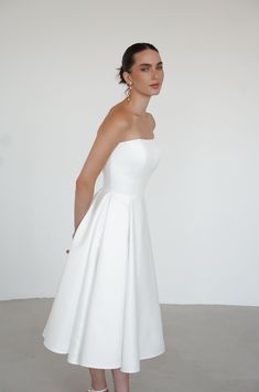 a woman in a white dress posing for the camera with her hands on her hips