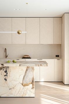 a kitchen with marble counter tops and white cabinetry, along with an island in the middle