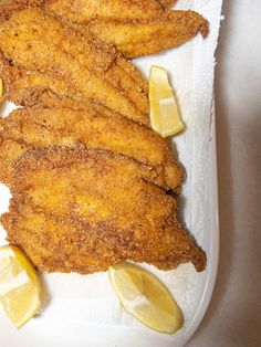 fried fish with lemon wedges on a white plate