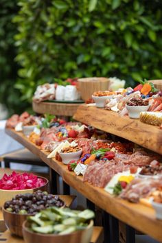 an assortment of meats and cheeses on wooden trays at a buffet table