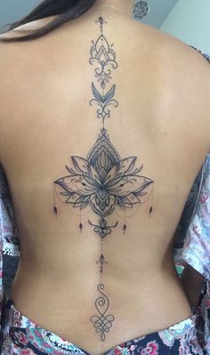 the back of a woman's lower back tattoo with an intricate design on it