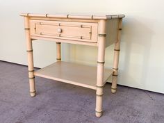 a small wooden table with two drawers on one side and a drawer on the other