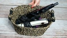 a person holding a hair dryer in a basket on top of a wooden floor