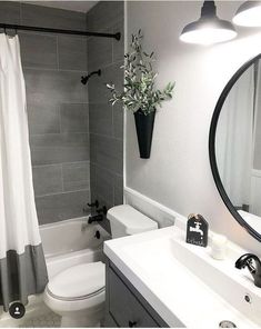 a white toilet sitting next to a bath tub in a bathroom under a mirror above a sink