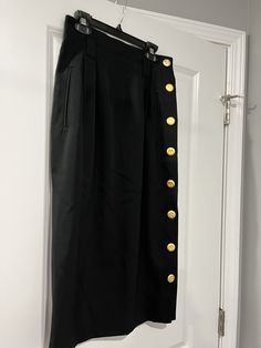 "Black skirt by I Magnin Design Studio.  Gold buttons down the side.  Size 8.  Pockets.  Shell 100% wool lining 100% acetate  Waist 27\" Length 30\" Has belt loops  G0065" Chic Formal Pencil Skirt With Button Closure, Elegant Black Pencil Skirt With Buttons, Elegant Skirt With Side Buttons, Gold Formal Skirt, Black Pencil Skirt With Button Closure For Work, Chic Fitted Skirt With Gold Buttons, Chic Skirt With Gold Buttons For Work, Black Pencil Skirt With Button Closure, Elegant Office Skirt With Side Buttons