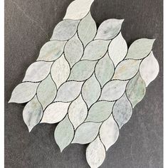 a white and gray mosaic tile with leaves on the bottom, sitting on a black surface