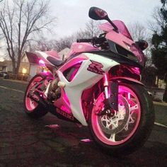 a pink and white motorcycle parked on the street