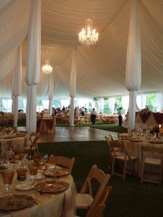 the inside of a large tent with tables and chairs set up for an event or party