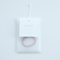 a white package with a pink bracelet on it and a tag that says falabe