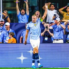 a soccer player is holding his arms in the air as he walks off the field