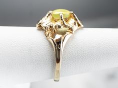 This vintage gold flower ring holds a rare gem mined in Sri Lanka and India for the most part, the stone is a cat's eye chrysoberyl. The soft, mossy yellow-green is reminiscent of a cat's eye, and the reflection of light inside this phenomenal stone gives the impression that the eye is watching, looking around where the hand is moved. Metal: 10K Yellow Gold Gem: Cat's Eye Chrysoberyl 1.56 Carats Gem Measurements: 7.1 mm, Round Ring Size: 7 Marks: "10K" Stamped on the inside band Chrysoberyl Ring, Yellow Gold Sapphire Ring, Gold Flower Ring, Right Hand Ring, Gem Mining, Gold Statement Ring, Floral Ring, Cameo Ring, Right Hand Rings