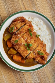 a white plate topped with meat and vegetables covered in gravy next to rice