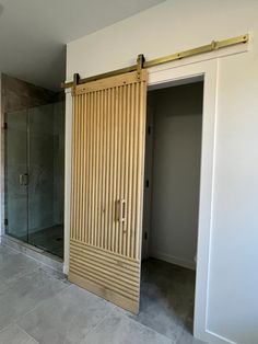 an empty room with sliding doors and tile flooring in the middle, next to a walk - in shower