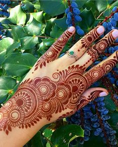 a woman's hand with henna on it and blue berries in the background