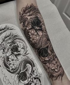 a dragon and skull tattoo on the arm, next to a white board with black ink