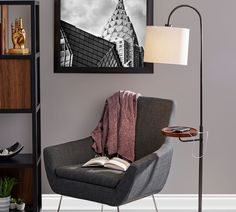 a chair with a blanket on it in front of a book shelf and a lamp