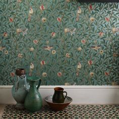 a room with green wallpaper and vases on the floor