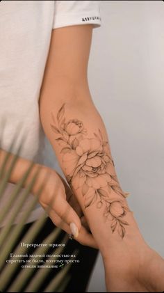 a woman's arm with flowers on it and her hand holding the wrist tattoo