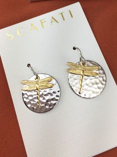 "The round brass drop is plated with a glossy silver alloy which is a mix of different base metals. The finish is glossy because it is rack plated. This means that the pieces are hand hung so they receive the optimal amount of coverage. Overlapping is an 18K gold plated dragonfly charm which compliments the silver round drop. The earrings are lead safe. The ear wires are surgical steel and comes with rubber back stoppers. The full length of earring is 1 & 1/4\"." Gold Dragonfly Earrings For Gift, Silver Dragonfly Earrings For Gift, Dragonfly Dangle Earrings, Gold Nickel-free Dragonfly Earrings, Nickel-free Gold Dragonfly Earrings, Dragonfly Earrings Brass, Navy Earrings, Nickel-free Sterling Silver Dragonfly Earrings, Silver Dragonfly Necklace