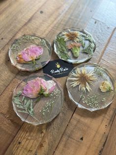 three glass plates with flowers in them on a wooden table